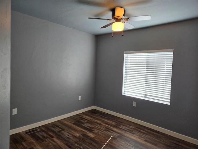 spare room featuring a ceiling fan, baseboards, visible vents, and dark wood-type flooring