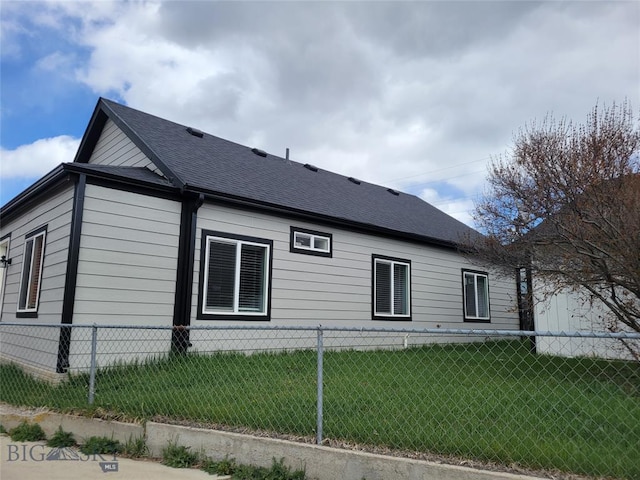 view of property exterior with roof with shingles, a lawn, and fence