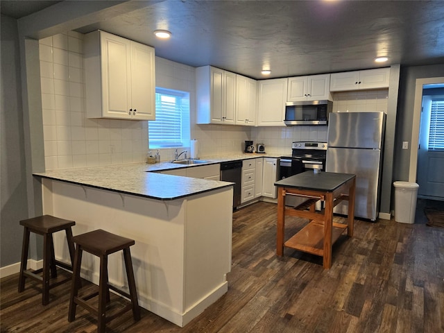 kitchen featuring stainless steel appliances, dark wood-type flooring, light countertops, and white cabinetry