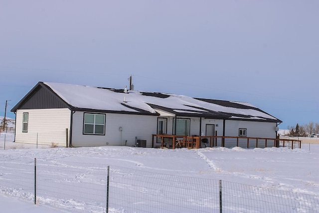 snow covered rear of property featuring central AC and fence