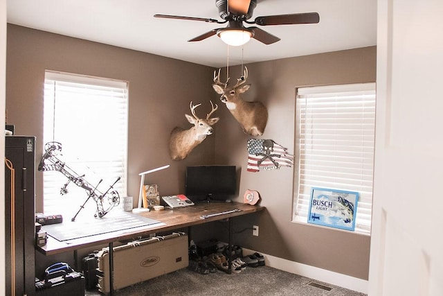 carpeted office space featuring visible vents, ceiling fan, and baseboards