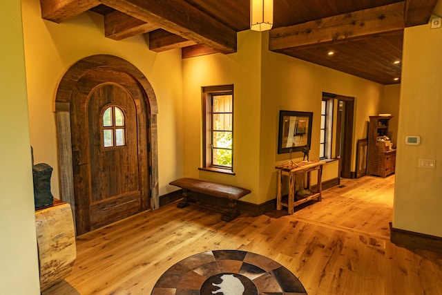 foyer entrance featuring beam ceiling, a healthy amount of sunlight, light wood-style flooring, and baseboards