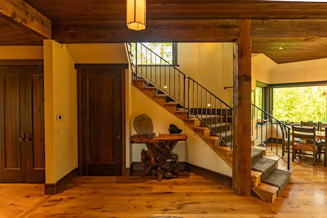 stairway featuring baseboards, wood finished floors, and beamed ceiling