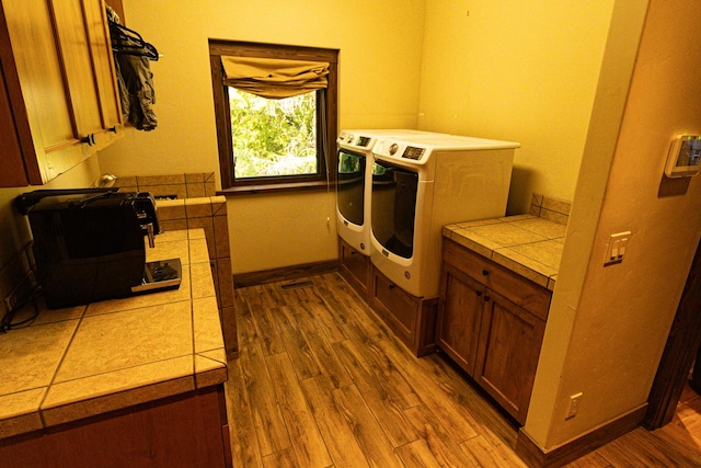 laundry room with light wood-type flooring, baseboards, and separate washer and dryer