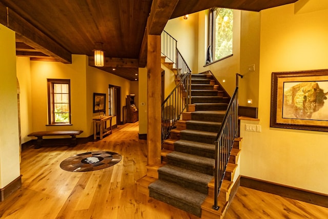 staircase with wooden ceiling, baseboards, wood finished floors, and beamed ceiling