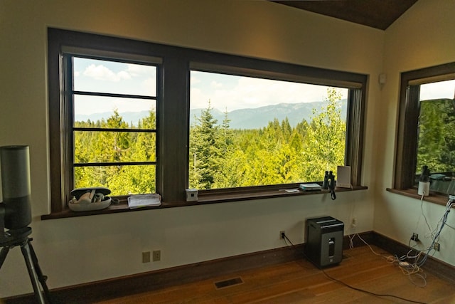 empty room with a healthy amount of sunlight, visible vents, a mountain view, and wood finished floors