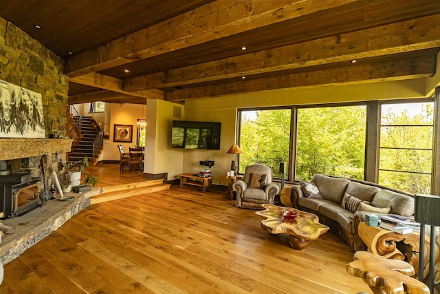 living area featuring stairs, light wood-type flooring, and beam ceiling