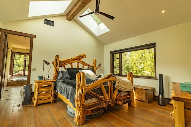 bedroom with a ceiling fan, multiple windows, beam ceiling, and wood finished floors