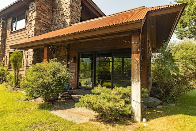 rear view of house with stone siding and a yard