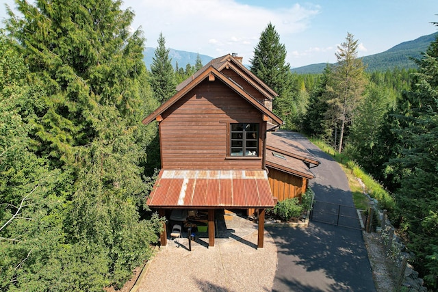 back of house featuring a chimney, metal roof, a gate, a mountain view, and a wooded view