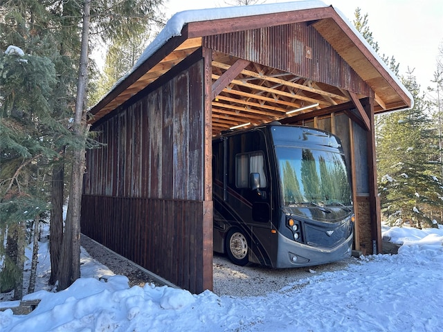 snow covered parking with a detached carport