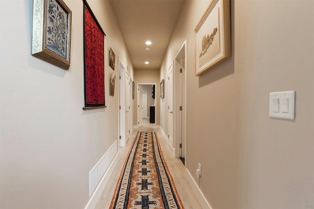 hallway with visible vents, baseboards, wood finished floors, and recessed lighting