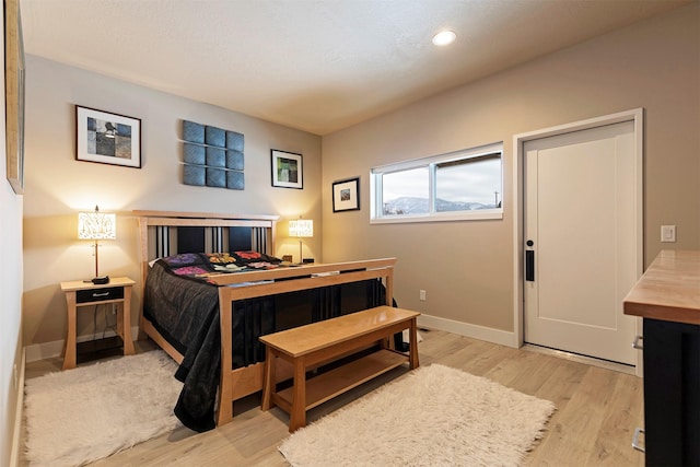 bedroom with a textured ceiling, light wood finished floors, recessed lighting, and baseboards