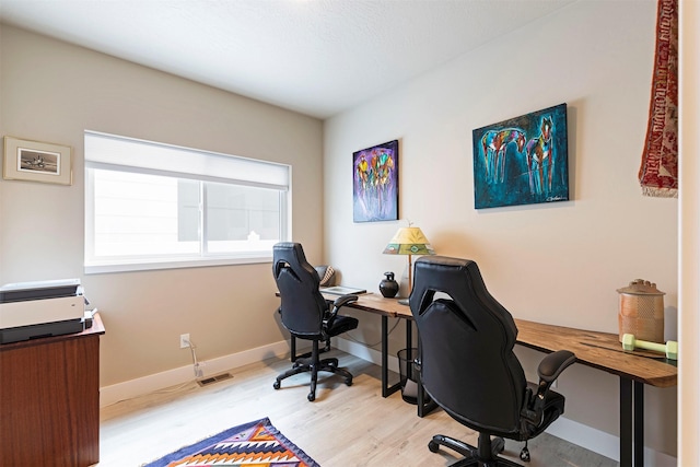 office featuring baseboards, visible vents, and light wood finished floors