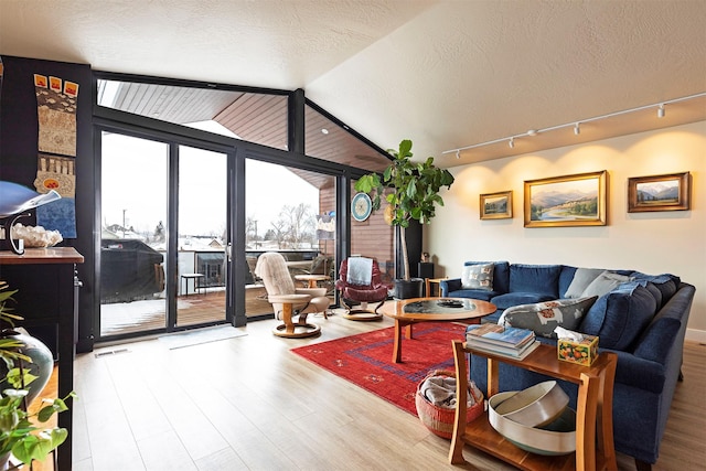 living room with a textured ceiling, expansive windows, wood finished floors, and lofted ceiling