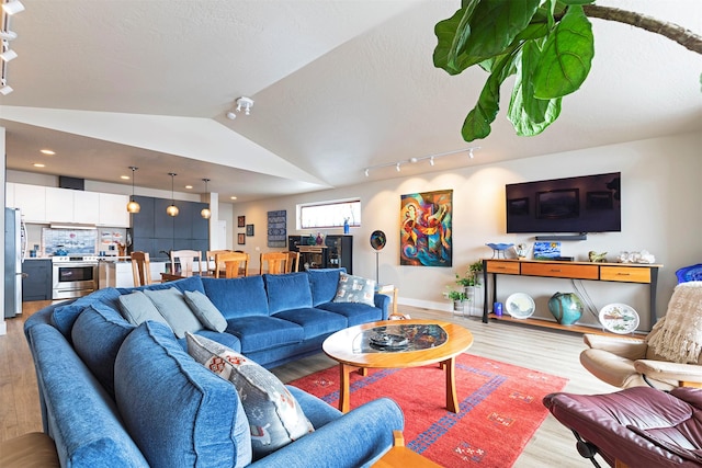 living room featuring light wood-style floors, lofted ceiling, a textured ceiling, and track lighting