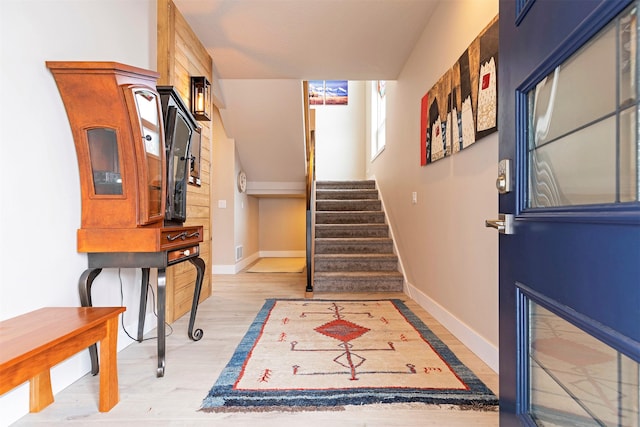 foyer with light wood-type flooring, stairs, and baseboards