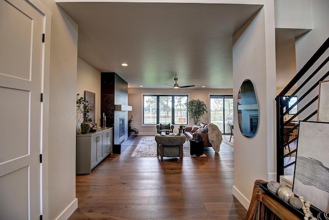 living room with dark wood-type flooring, a large fireplace, baseboards, and stairs