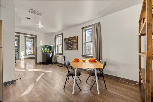 dining room featuring visible vents, baseboards, and wood finished floors