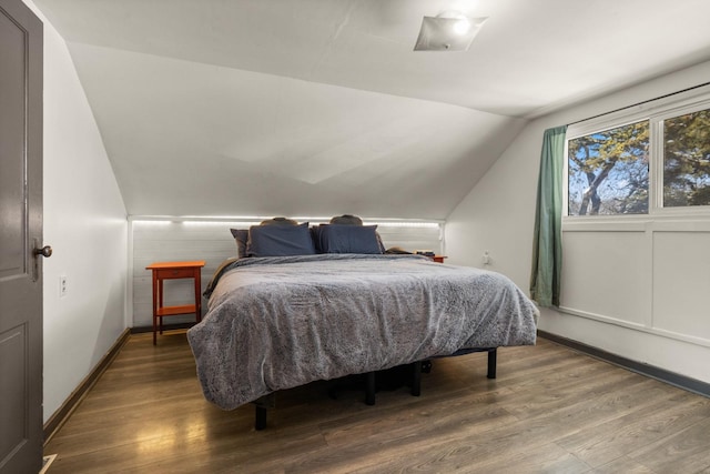 bedroom with lofted ceiling, baseboards, and wood finished floors