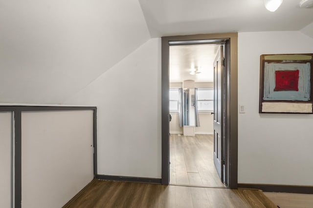 interior space with dark wood-type flooring, lofted ceiling, and baseboards