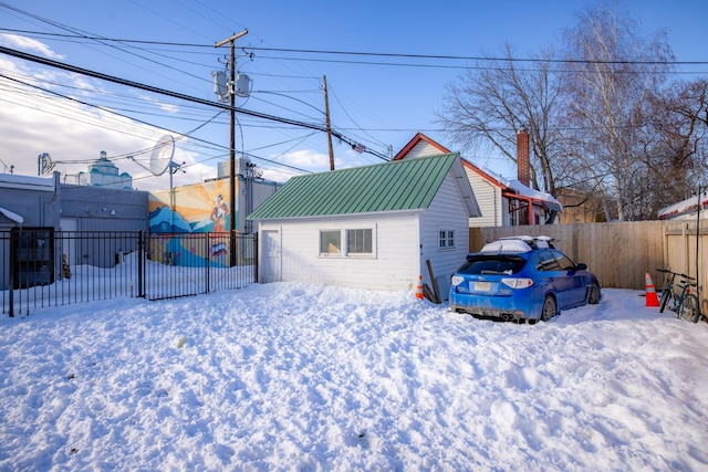 exterior space with metal roof, a chimney, and fence