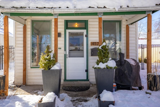 snow covered property entrance with faux log siding and fence