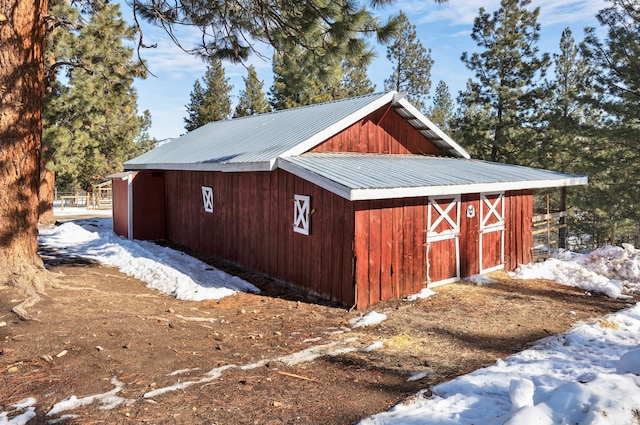 snow covered structure with an outbuilding