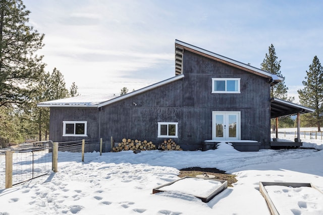 snow covered property featuring french doors and fence