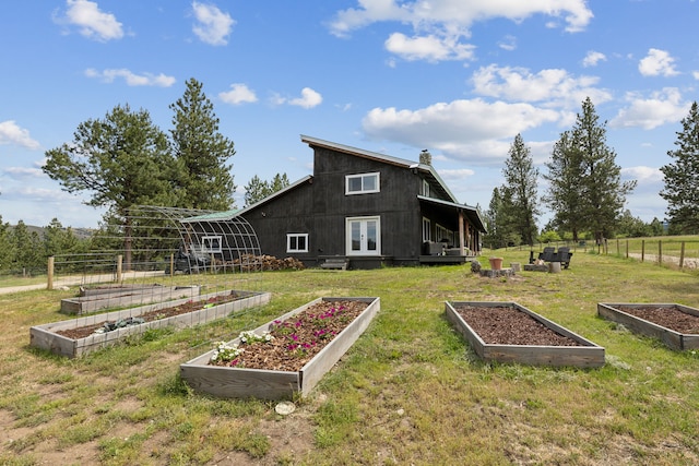 back of property featuring a vegetable garden, french doors, and a lawn