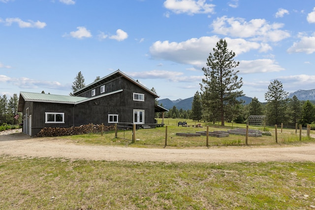 view of home's exterior with metal roof, a rural view, a mountain view, a yard, and a vegetable garden