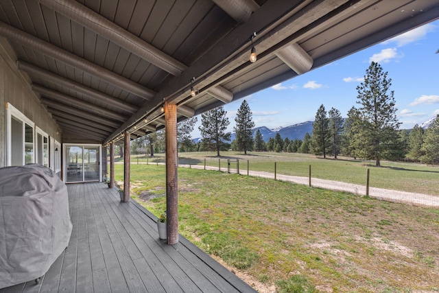 wooden terrace featuring a rural view, a mountain view, and a yard