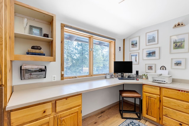 office area featuring built in study area, vaulted ceiling, and light wood-style flooring