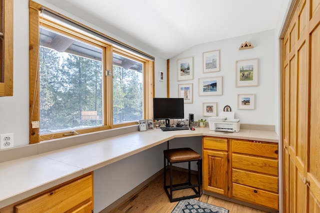 office space featuring lofted ceiling, light wood-type flooring, and built in study area