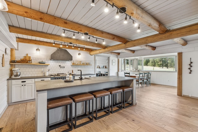 kitchen featuring light wood finished floors, wall chimney exhaust hood, white cabinetry, and open shelves