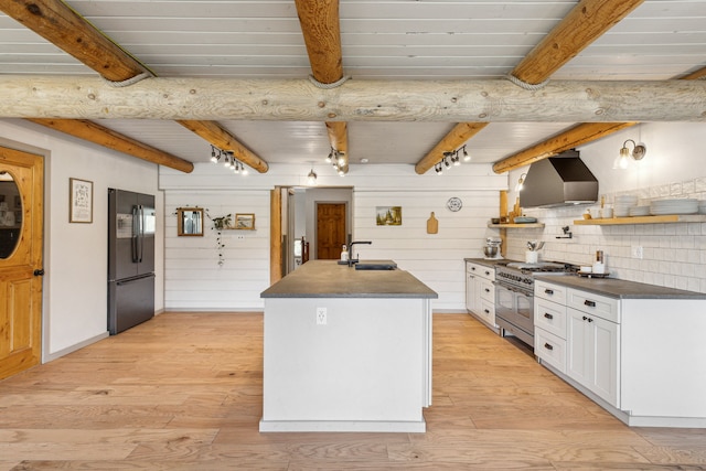 kitchen featuring range with two ovens, white cabinetry, freestanding refrigerator, wall chimney exhaust hood, and dark countertops