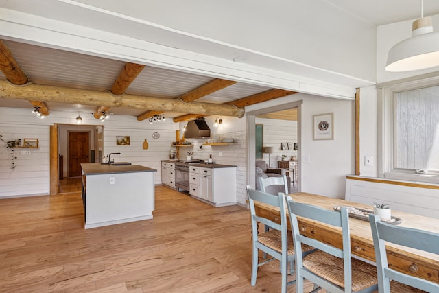 kitchen with stainless steel stove, a sink, white cabinets, light wood-type flooring, and dark countertops