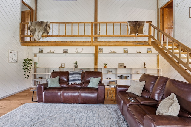 living room featuring wood walls, stairs, and wood finished floors