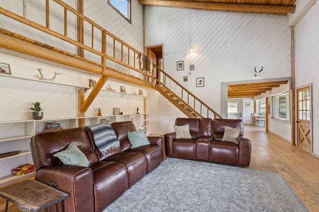 living room with a towering ceiling, wood walls, stairs, and hardwood / wood-style floors