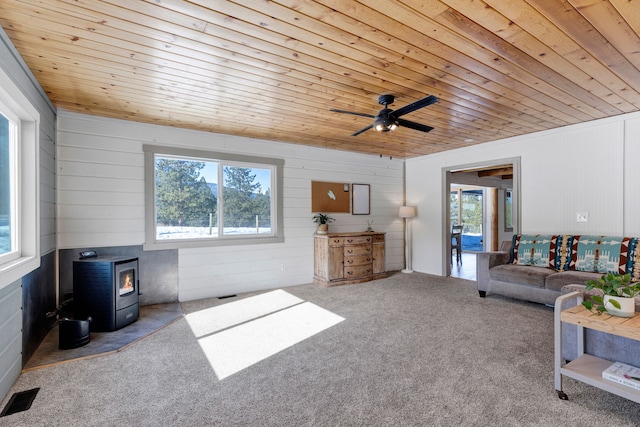 living area featuring wood ceiling, a wealth of natural light, visible vents, and a wood stove