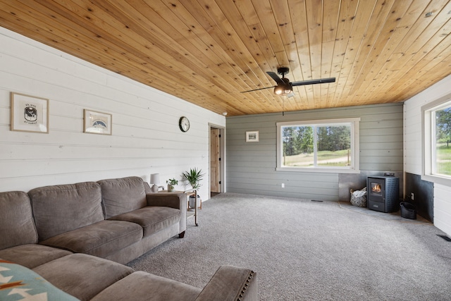 carpeted living area featuring a wood stove and wood ceiling