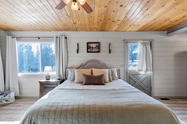 bedroom with light wood-style floors, wooden ceiling, and multiple windows