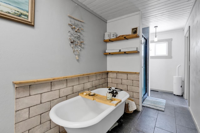 bathroom featuring tile patterned flooring, a freestanding tub, crown molding, and tile walls