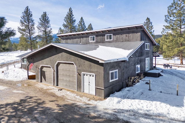 view of snow covered exterior featuring a detached garage and metal roof