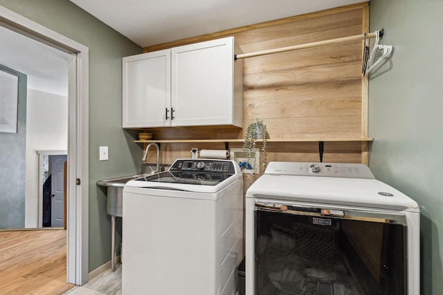 laundry area featuring cabinet space, light wood finished floors, and washing machine and clothes dryer