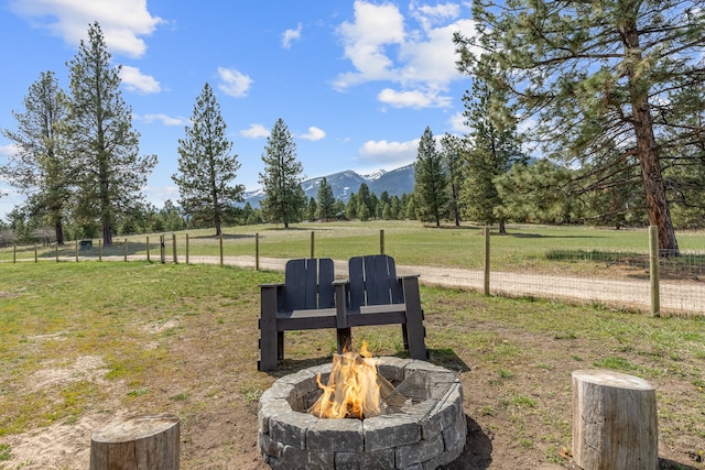 view of yard featuring an outdoor fire pit, a rural view, a mountain view, and fence