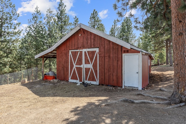 view of outdoor structure featuring fence and an outbuilding