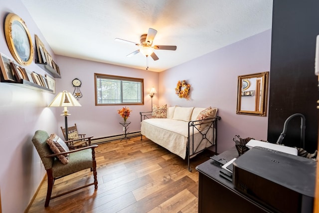 bedroom with light wood finished floors, a baseboard radiator, and ceiling fan