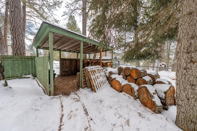 snowy yard with a carport and fence