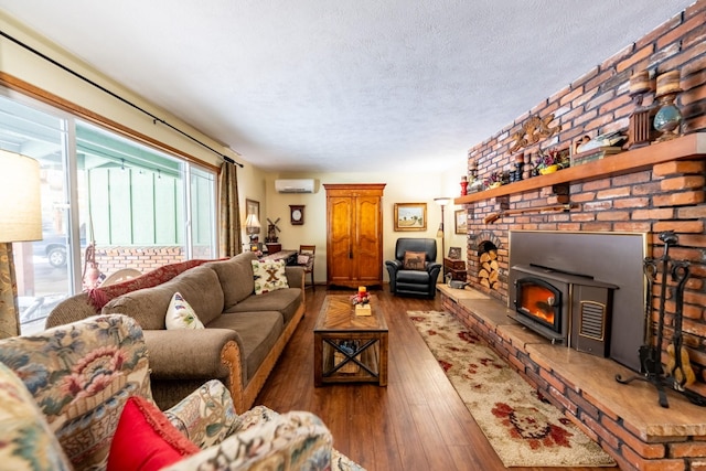 living area featuring a textured ceiling, hardwood / wood-style floors, a wall mounted air conditioner, and a fireplace